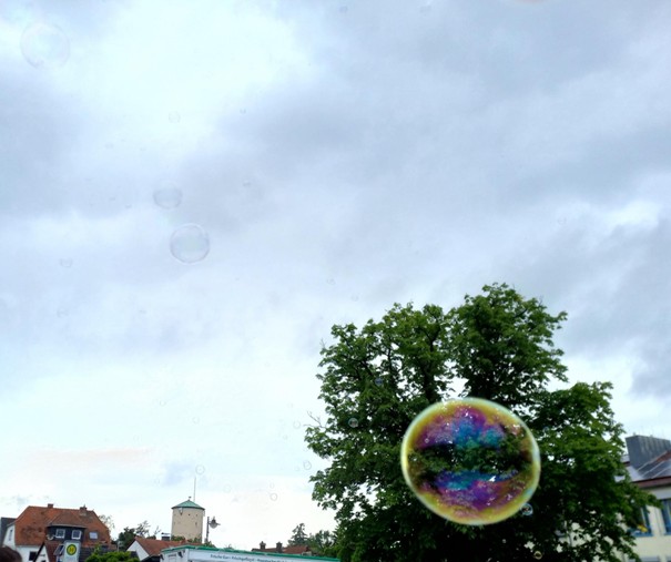 Himmel über Kahl mit einer bunten Seifenblase im Vordergrund. Im Hintergrund erkennt man den Wasserturm.