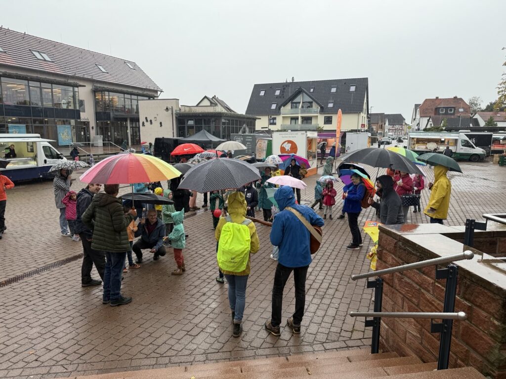 Menschen mit Regenschirmen auf dem Kahler Dorfplatz