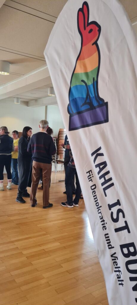 Seminar Teilnehmende stehend mit Kahl ist bunt Banner im Vordergrund