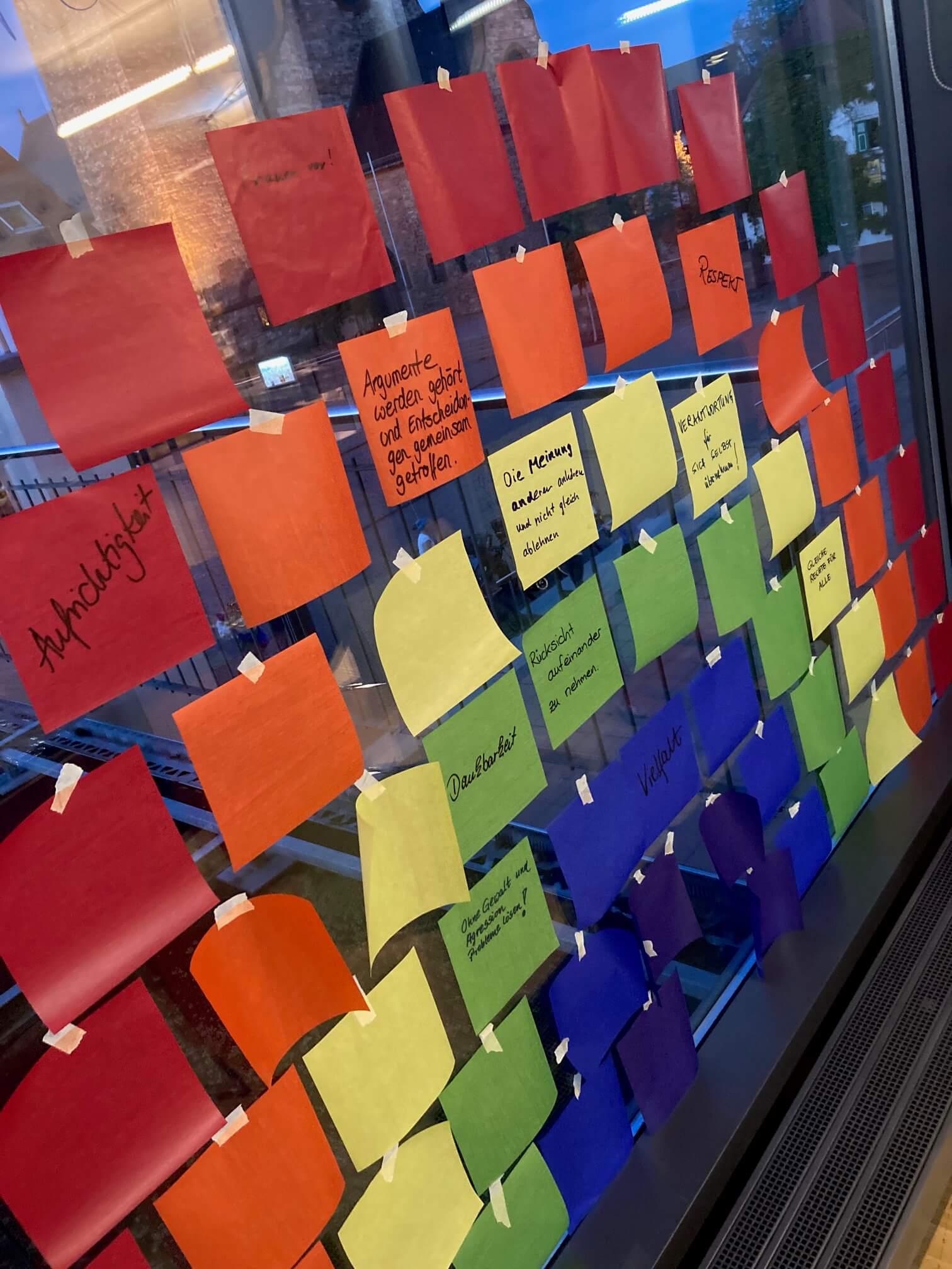 Post-Its wie ein Regenbogen angeordent auf einer Scheibe